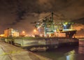 Container terminal unloading a moored vessel at night.