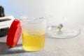 Container with urine sample for analysis and test strips on grey table in laboratory, closeup. Space for text Royalty Free Stock Photo