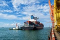 Container vessel berthing at an industrial port. Tugboat push large cargo vessel to berth at port terminal.