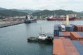 Container vessel with crane leaving the port with assistance of tugboat which is pushing in bow. Royalty Free Stock Photo