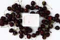 Container with yogurt and a bunch of fresh cherry berries on whi Royalty Free Stock Photo