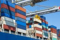 Containers being discharged from a large container ship by a crane in the port of Rotterdam, Europe