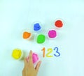 Containers with colorful plasticine and the child made numbers one , two, three.  white  wooden background Royalty Free Stock Photo