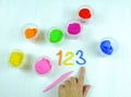 Containers with colorful plasticine and the child made numbers one , two, three.  white  wooden background Royalty Free Stock Photo