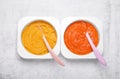 Containers with healthy baby food and spoons on white textured table, flat lay