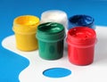 Containers of watercolor paints and white paintbrushes palette on blue background