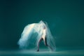 Contemp dance. Creative portrait of flexible ballet dancer in motion with white cloth over green blue background. Art