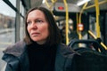 Contemplative adult caucasian woman riding public transportation bus through city streets Royalty Free Stock Photo