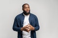 A contemplative African-American man stands with clasped hands