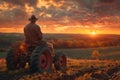 Farmer on old tractor overlooking sunset landscape