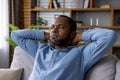 Contemplative man relaxing on sofa with hands behind head Royalty Free Stock Photo