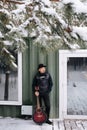 Contemplative musician in a hat and leather jacket standing next to a house door