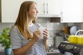 Contemplative woman holding a coffee mug in a sunlit kitchen Royalty Free Stock Photo