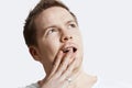 Contemplative young man with hand over mouth against white background Royalty Free Stock Photo