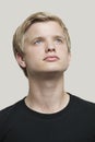 Contemplative young man looking up against gray background Royalty Free Stock Photo