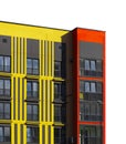 Contemporary apartment building with bold yellow and red facade elements, featuring vertical stripe Royalty Free Stock Photo
