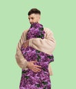 Contemporary art collage. Man lovely hugging silhouette of woman filled with flowers isolated over mint background