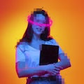 Contemporary artwork. Ypung girl with pixel head and neon lettering around holding tablet isolated over orange