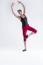 Contemporary Ballet of Flexible Athletic Man Posing in Red Tights in Ballanced Dance Pose With Hands Lifted in Studio on White