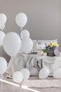 Contemporary bedroom interior design with comfortable bed with grey sheets, flowers round boxes and white balloons