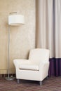 Contemporary beige comfortable armchair with lamp. Furniture