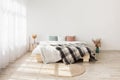 Contemporary boho design in minimalist. Bed with pillows and blanket, table with dry plants in vases Royalty Free Stock Photo