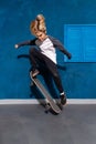 Stylish teen doing skateboard trick by jumping up