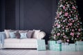 Contemporary Christmas New Year interior decoration: fir tree decorated with pink and turquoise balls and gift boxes under it.