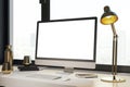 Contemporary designer desktop with empty white computer monitor, lamp, supplies and other items. Window with city view in the Royalty Free Stock Photo