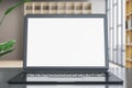 Contemporary designer office desk with empty white mock up laptop screen and other items on blurry office background. Royalty Free Stock Photo