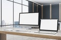 Contemporary designer office desktop with empty white mock up computer screens, supplies and blurry interior with windows and city