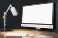 Contemporary designer wooden desktop with empty white mock up computer monitor, lamp and keyboard. Royalty Free Stock Photo