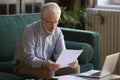 Contemporary elderly man consider paperwork paying bills online