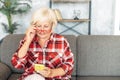 Senior woman sits on the sofa with smartphone