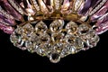 Contemporary gold chandelier isolated on black background. Crystal chandelier decorated Pink crystals close-up Royalty Free Stock Photo