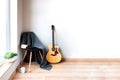 Contemporary home interior. Black chair covered with woolen gray blanket and acoustic guitar in front of an empty white wall. Time Royalty Free Stock Photo