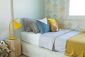 Kid bedroom in blue and yellow tone pillow with many doll on bed.