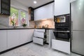 A contemporary kitchen with white cabinets, a marble floor, an open oven door, and pull-out shelves