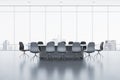 Contemporary meeting room interior with reflections on concrete flooring and panoramic window with city view and daylight. Royalty Free Stock Photo