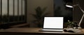 A contemporary office at night features a white-screen laptop computer mockup on a wooden desk Royalty Free Stock Photo