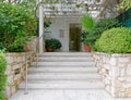 Contemporary residential apartment building entrance with plants and stairs to glass door