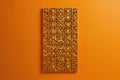 A contemporary wall hanging with intricate geometric tessellations, isolated on a solid amber background