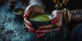 Contemporary Witch Aesthetic: Tattooed Hands, Rings, and Red Nails Graciously Hold a Mystical Cup of Matcha Latte