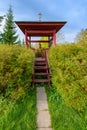 Contemporary wooden belltower with bronze bells and golden cross on top at sunny autumn day