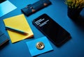 Modern workspace with smartphone, Bitcoin coin, and stationery on blue desk Royalty Free Stock Photo