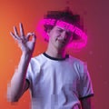 Contemporay artwork. Emotive youg man with neon lettering around pixel head showing OK gesture over pink