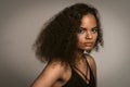 Contempt or hate African American girl with afro hair standing in black bare shoulder top isolated on grey background