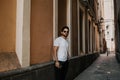 Content attractive hispanic man in white tshirt walking old town streets holding mobile phone hand.Bearded hipster male Royalty Free Stock Photo