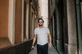 Content attractive hispanic man in white tshirt walking old town streets holding mobile phone hand.Bearded hipster male Royalty Free Stock Photo