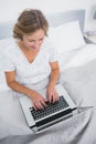 Content blonde woman in bed using her laptop Royalty Free Stock Photo